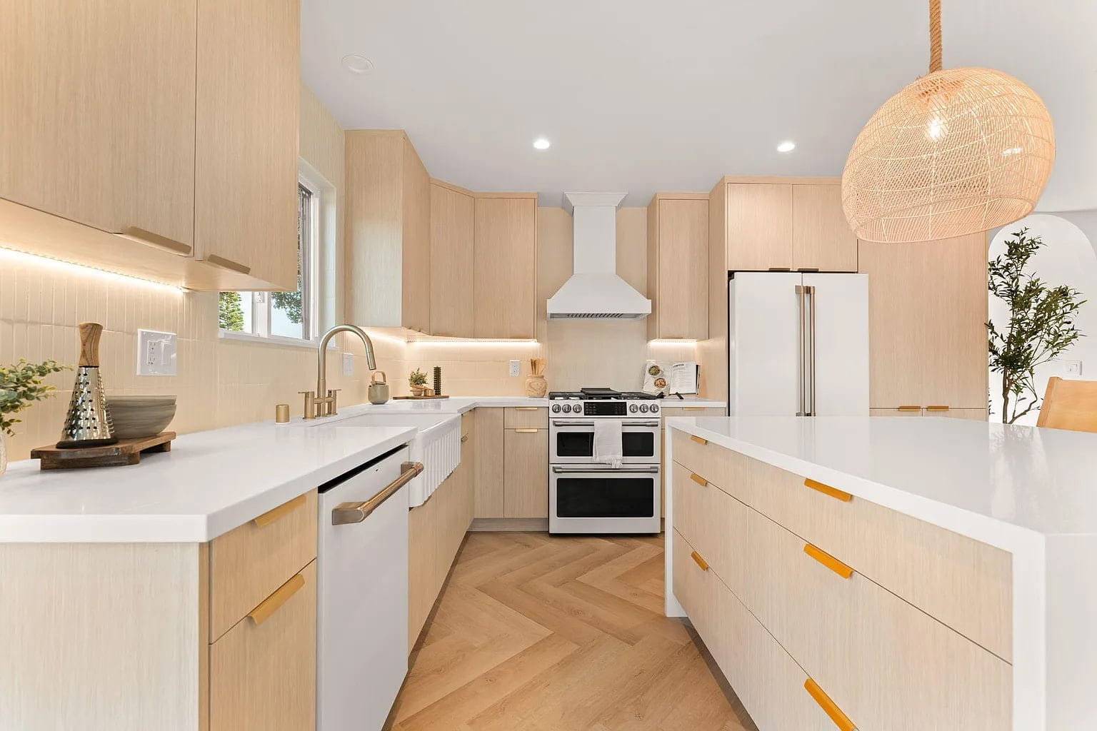 Kitchen with white oak cabinetry, a farmhouse sink, gas range under a plaster hood, and herringbone wood floors, DHRH Campanil renovation