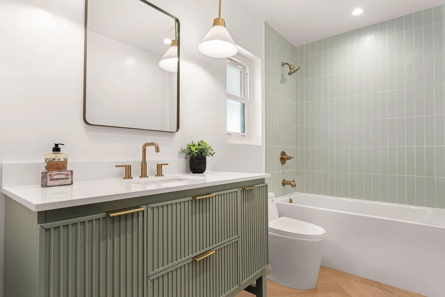 Bathroom with a sage green fluted vanity, brass fixtures, and a green-tiled tub-shower combo, DHRH Campanil renovation