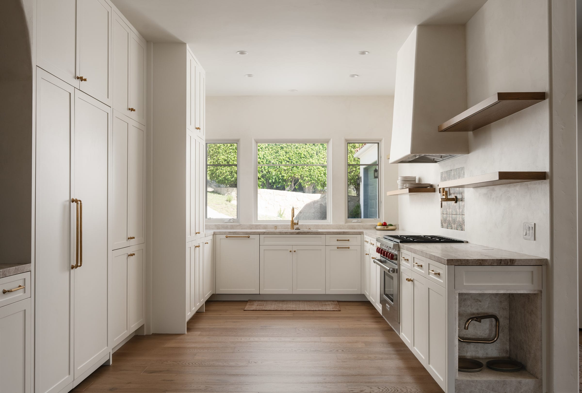 Kitchen with white shaker cabinetry, brass hardware, a plaster range hood, and stone countertops, DHRH Mission Canyon renovation