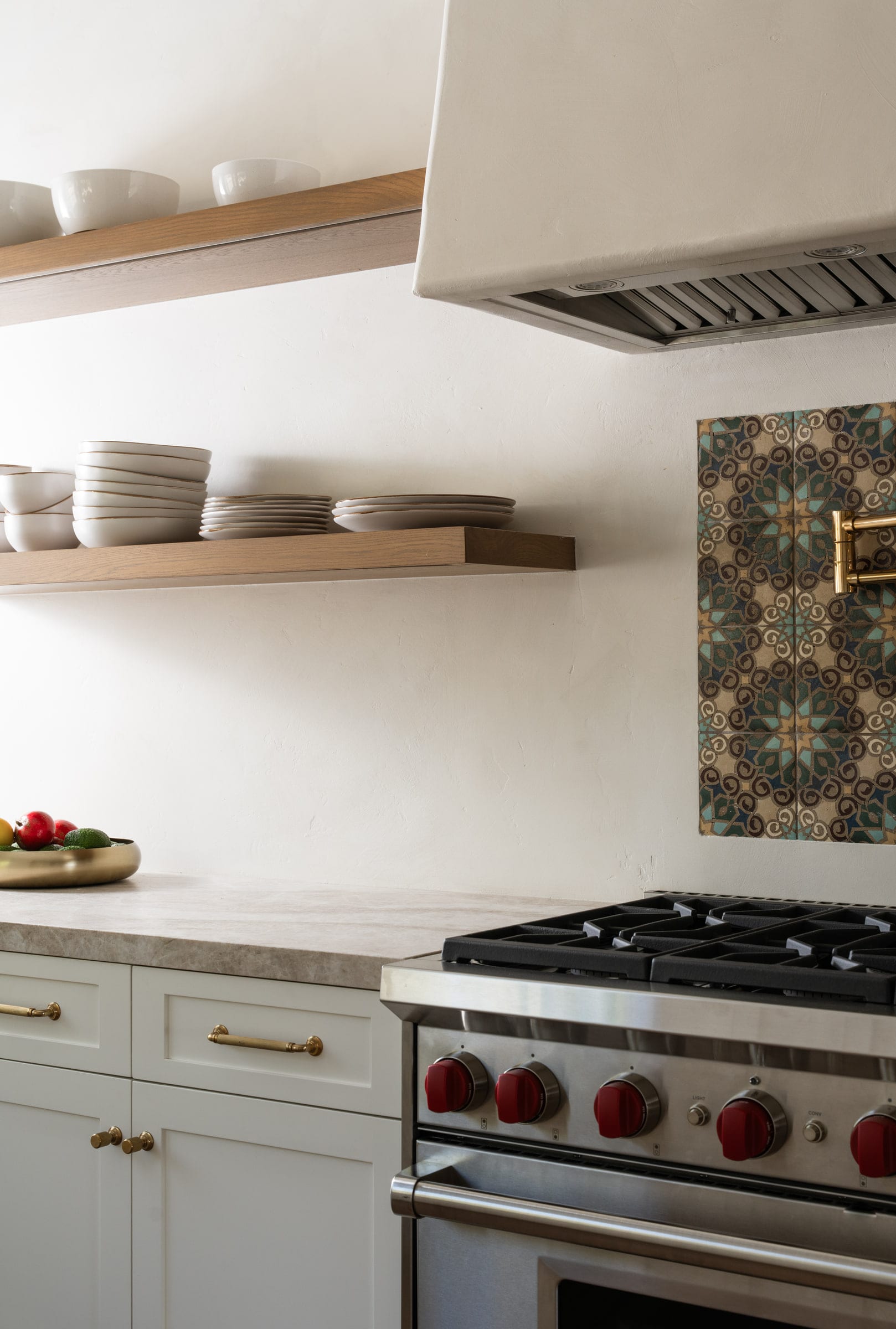 Kitchen detail with floating wood shelves, a patterned tile backsplash, and a brass pot filler over the range, DHRH Mission Canyon renovation
