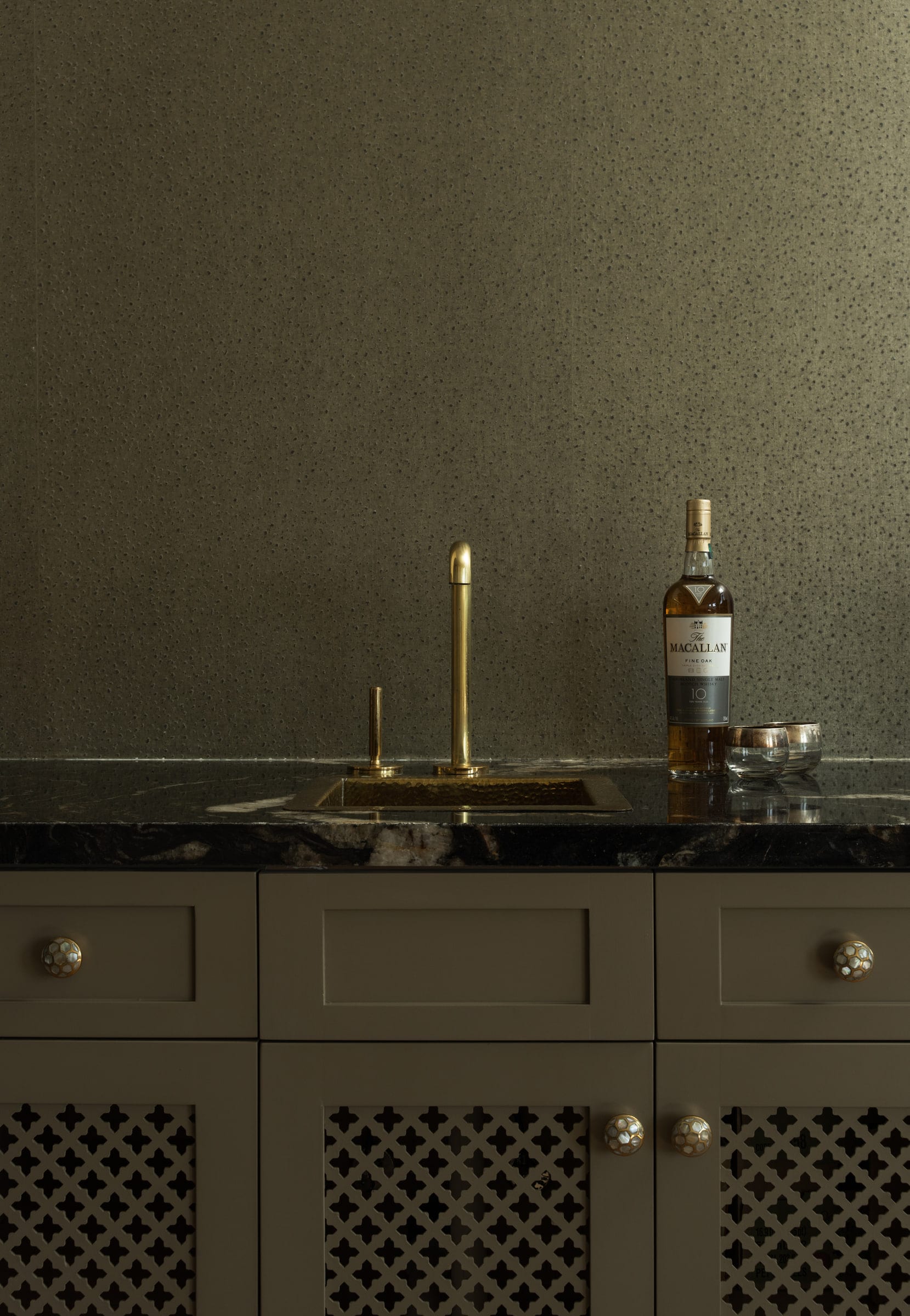 Wet bar with a hammered brass sink, black marble counter, and mother-of-pearl cabinet hardware, DHRH Mission Canyon renovation