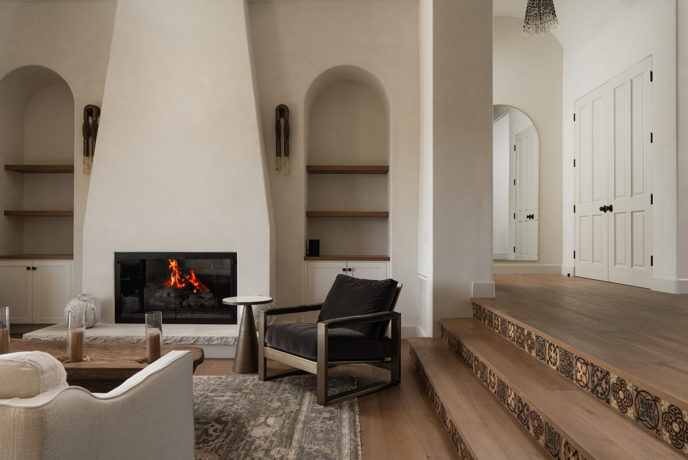 Living room fireplace with arched plaster niche shelving and a brass-framed black velvet armchair, DHRH Mission Canyon renovation