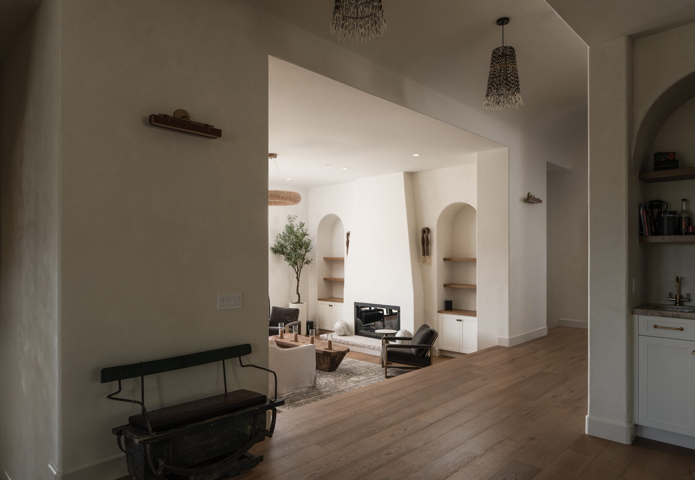 Living room with a plaster fireplace, woven pendant lights, and patterned tile steps leading to a hallway, DHRH Mission Canyon renovation