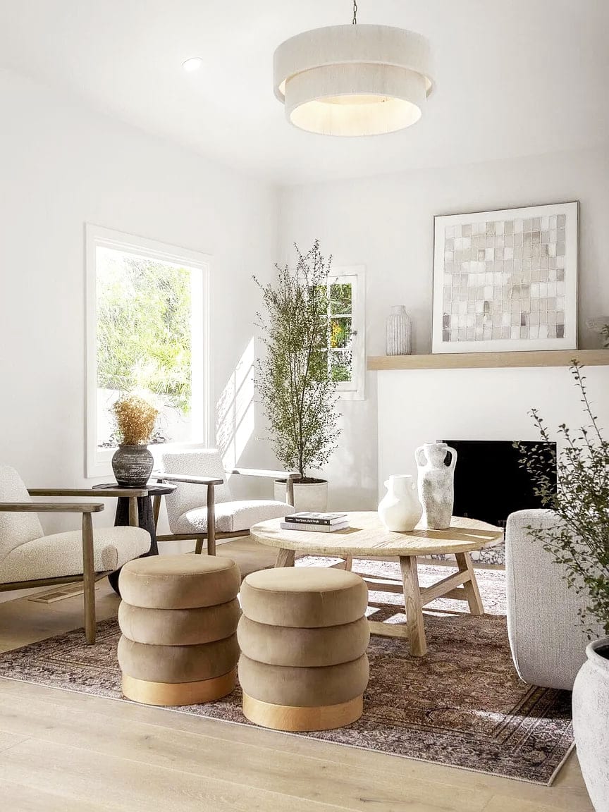 Living room seating with leather poufs and a round oak coffee table by the fireplace, DHRH Montecito renovation