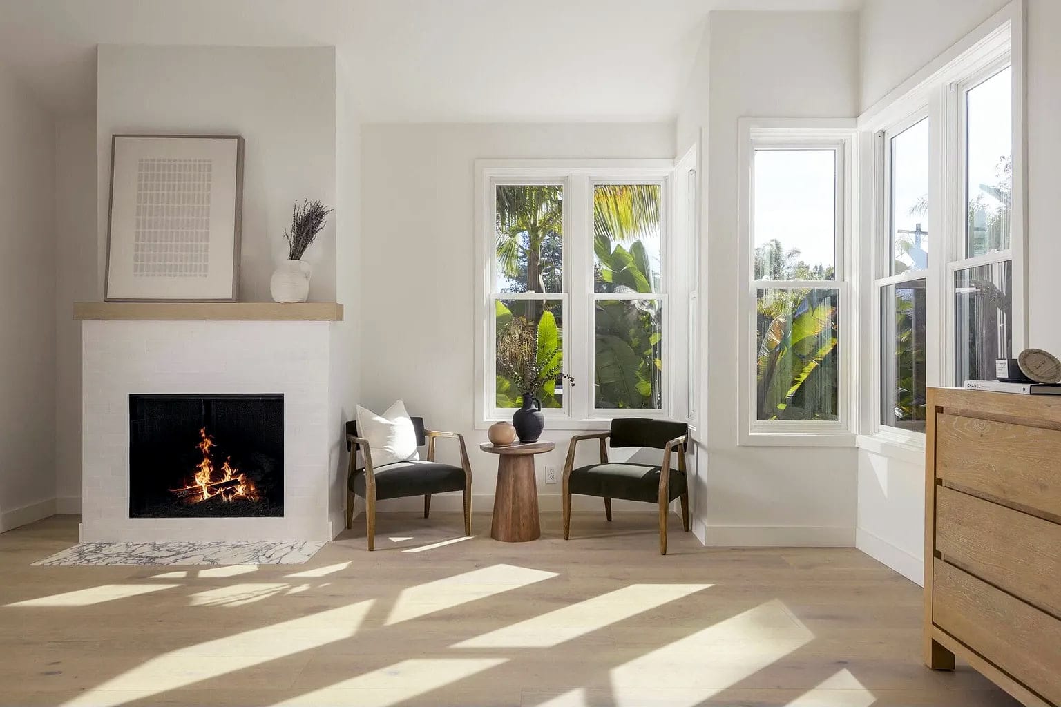 Primary bedroom sitting area with a white brick fireplace and windows to the palms, DHRH Montecito renovation