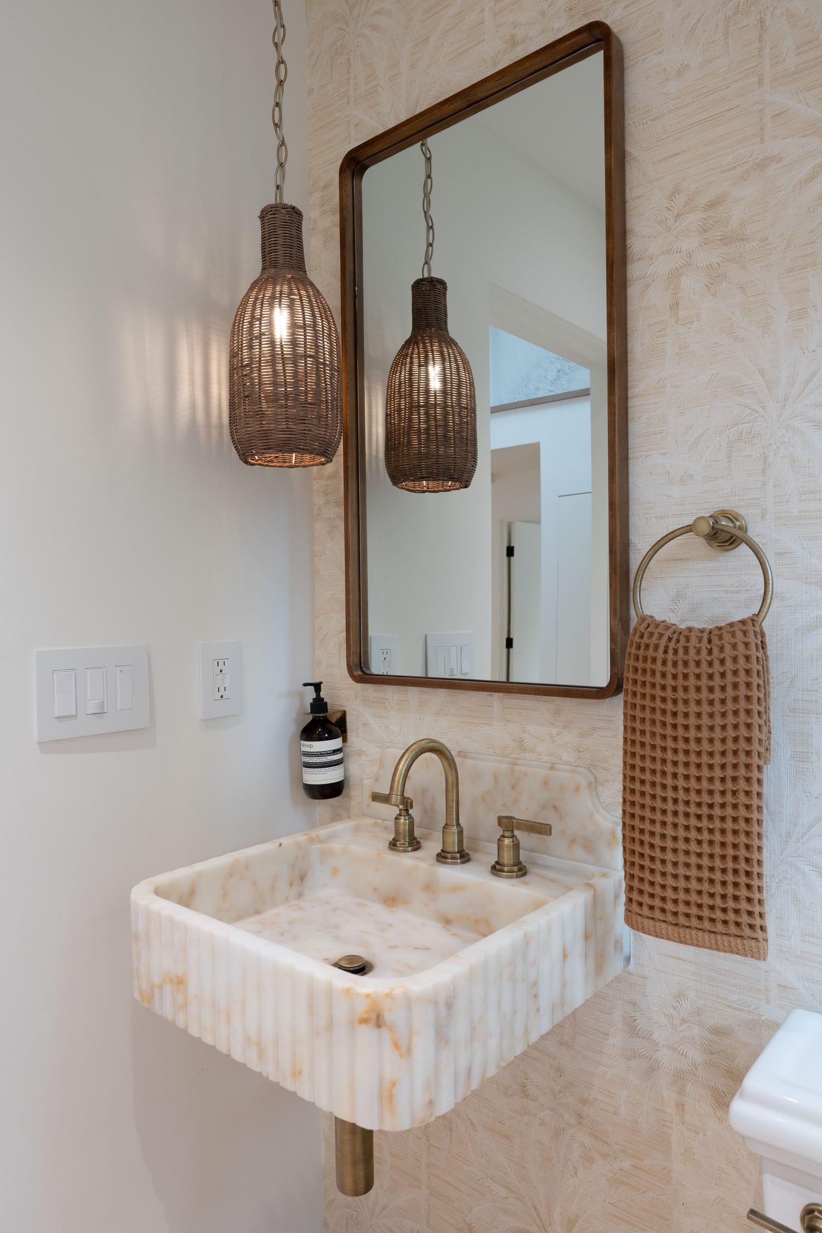 Powder room with a fluted white marble sink, brass gooseneck faucet, and a woven rattan pendant light, DHRH Padaro Lane renovation