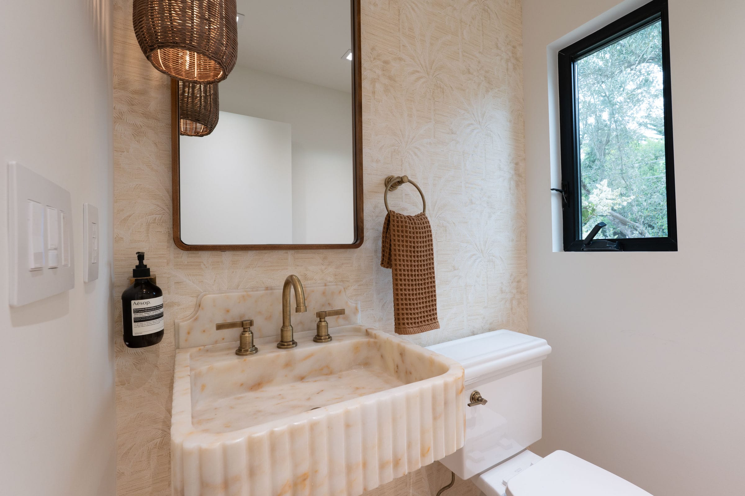 Powder room with palm-print wallpaper, a black-framed garden window, and a wall-mounted toilet, DHRH Padaro Lane renovation