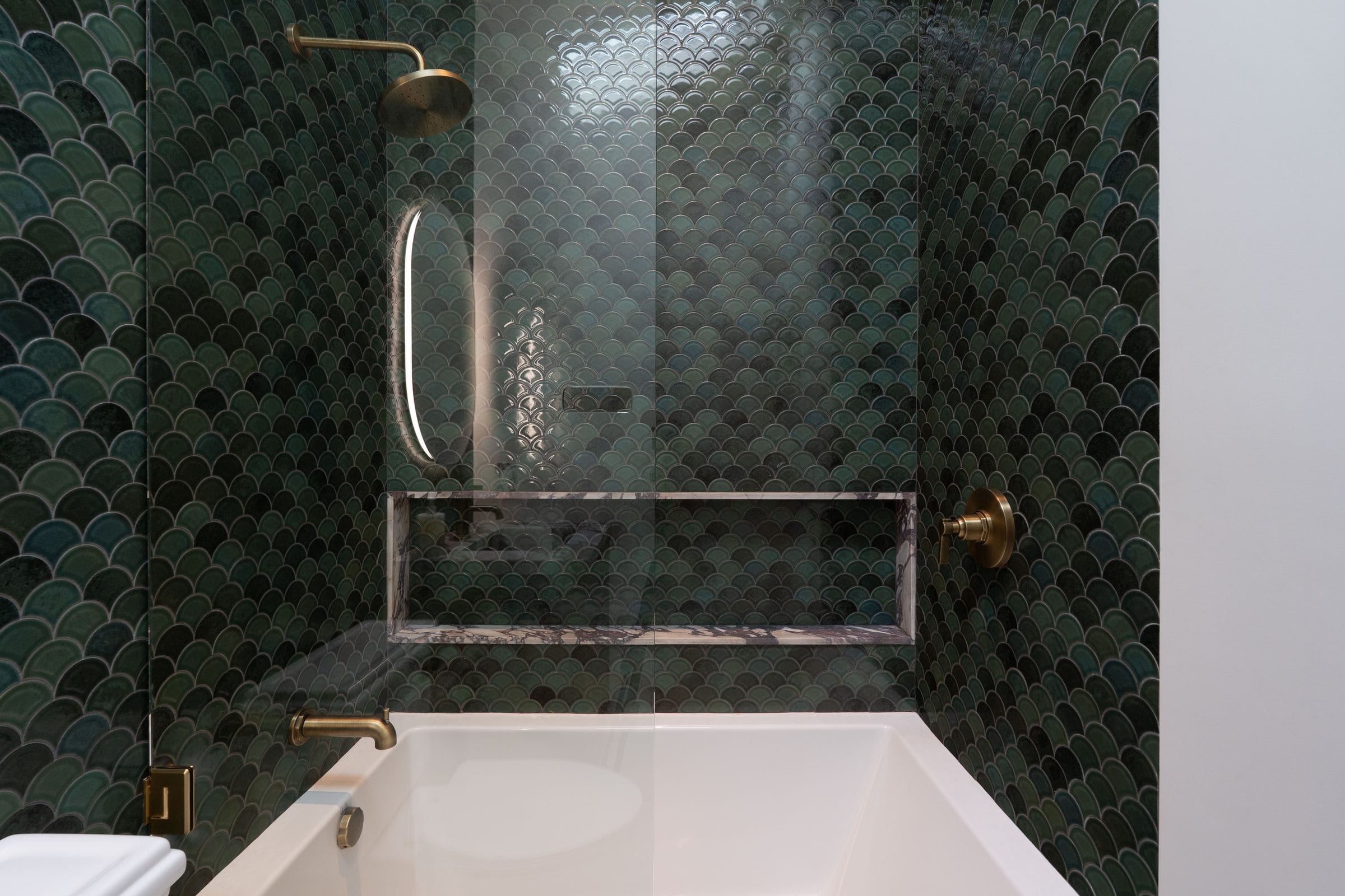 Bathroom tub and shower in dark green fish-scale tile with brass fixtures and a marble niche shelf, DHRH Padaro Lane renovation