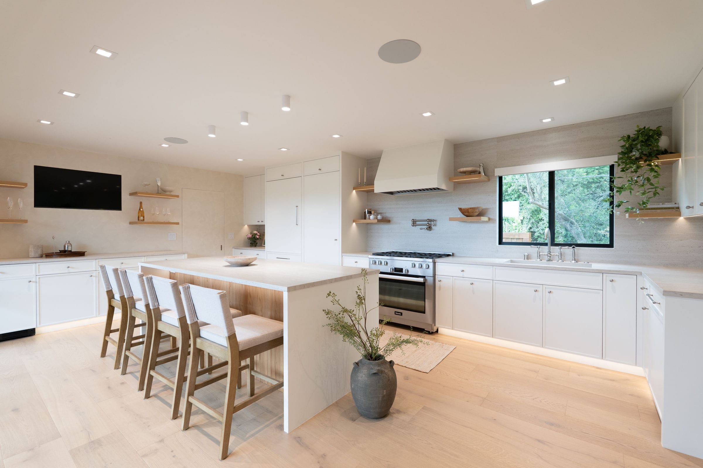 Kitchen island with counter seating facing an open-shelf range wall and a window over the sink, DHRH Padaro Lane renovation