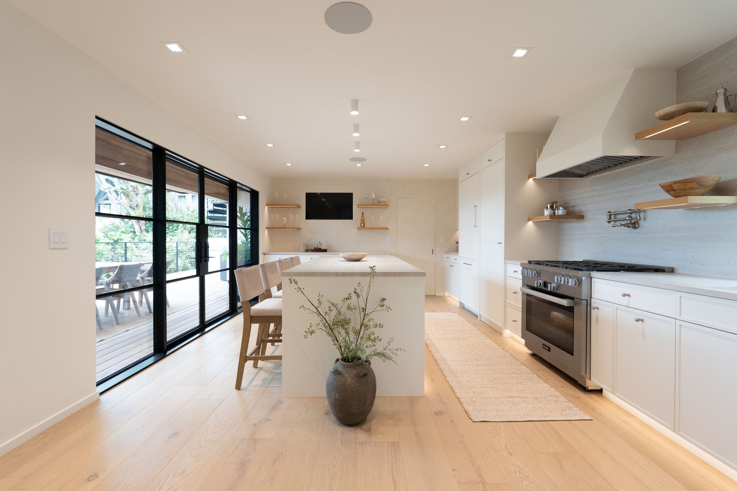 Kitchen view toward the range wall with steel-framed sliding doors open to the deck, DHRH Padaro Lane renovation