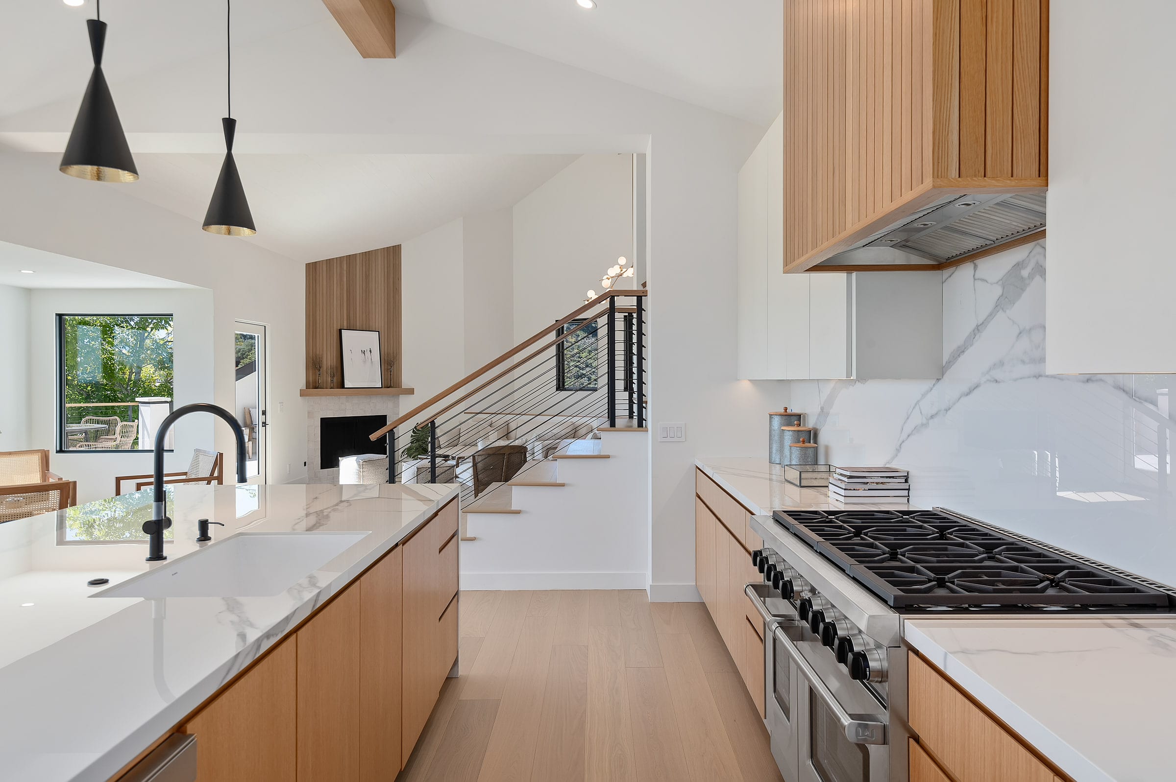 Kitchen counter with a gas range and marble backsplash, staircase and fireplace visible beyond, DHRH Riviera renovation