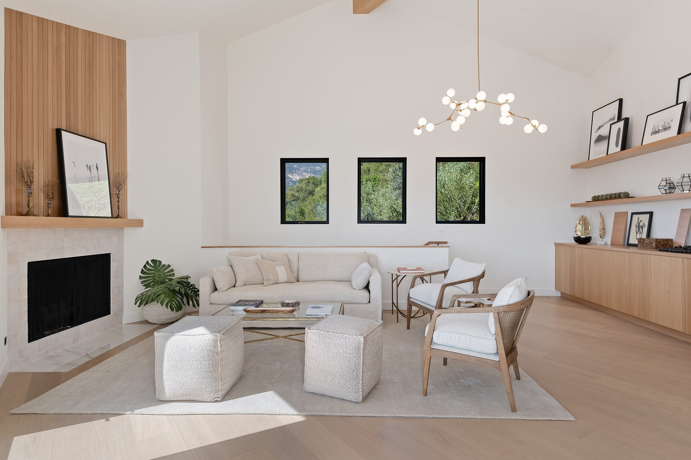 Living room with a wood-paneled fireplace, tiled hearth, and built-in wood shelving displaying framed art, DHRH Riviera renovation