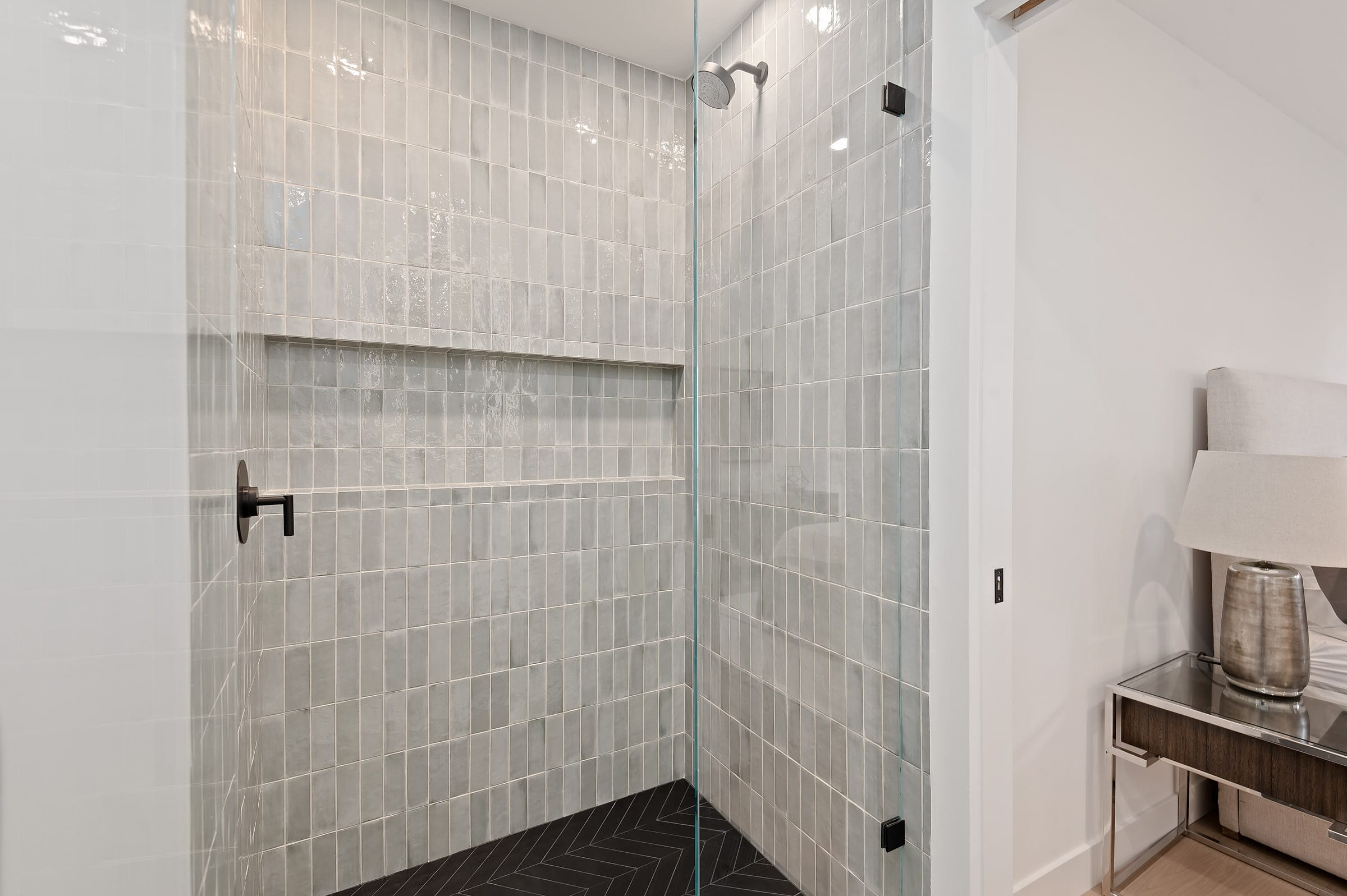 Walk-in shower with vertical tile, a black herringbone floor, and a tiled niche shelf, DHRH Riviera renovation