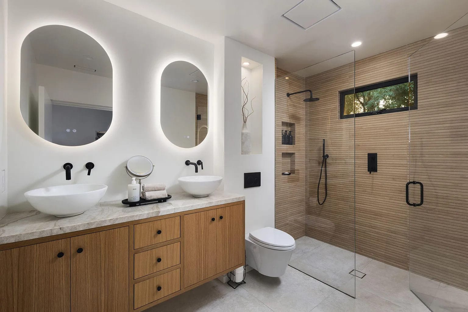 Primary bath with dual backlit oval mirrors, vessel sinks, and a wood-tile glass shower, DHRH San Roque renovation