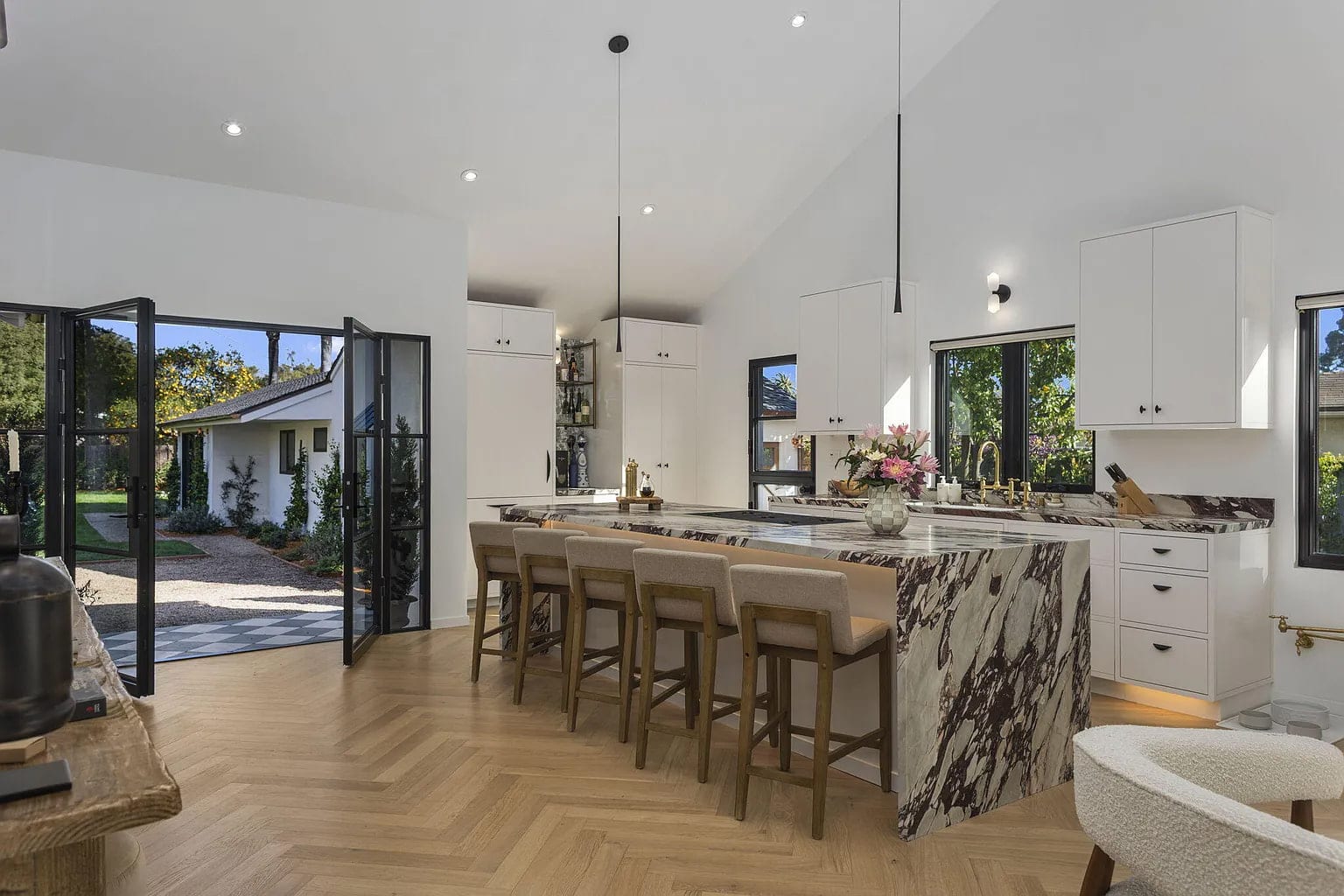 Vaulted great room with herringbone oak floors and a waterfall marble kitchen island, DHRH San Roque renovation