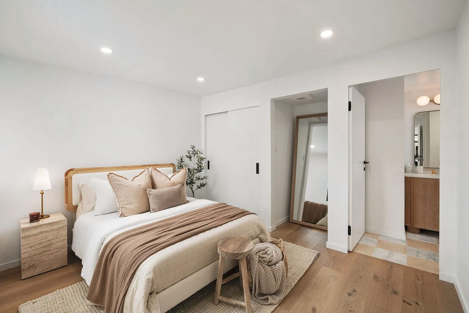 Primary bedroom with a cane headboard opening to an ensuite bath and walk-in closet, DHRH San Roque renovation