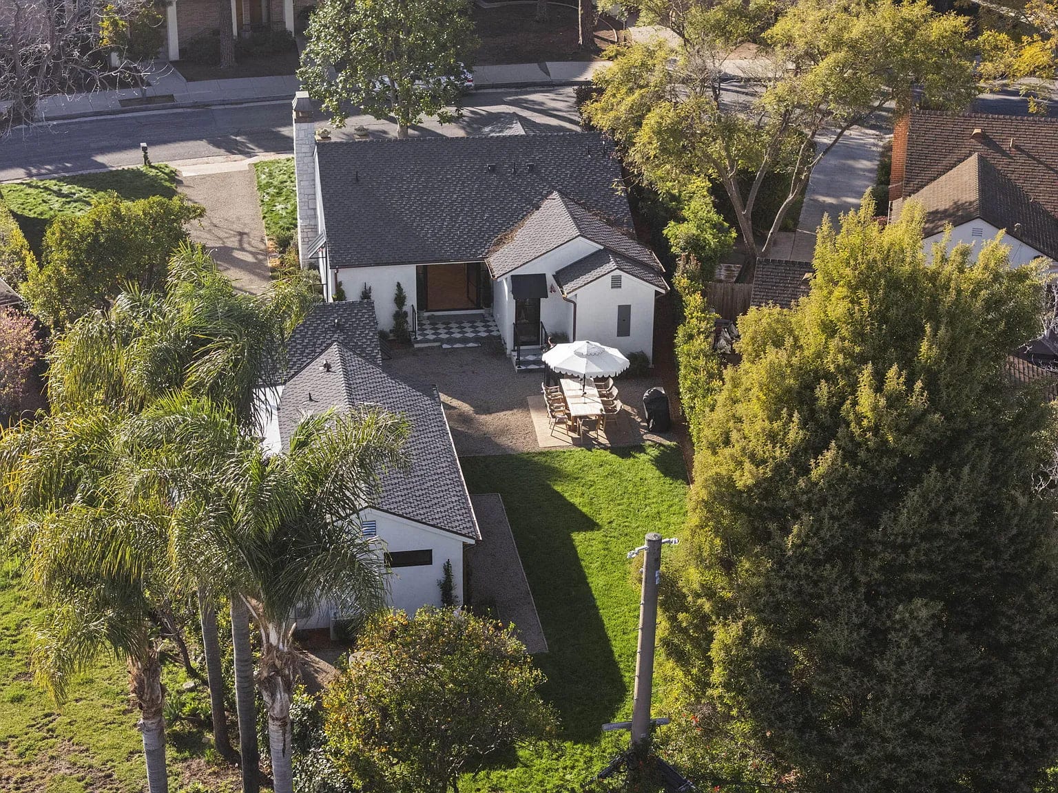 Aerial view of the property's gabled roofs, checkered tile patio, and backyard dining area, DHRH San Roque renovation