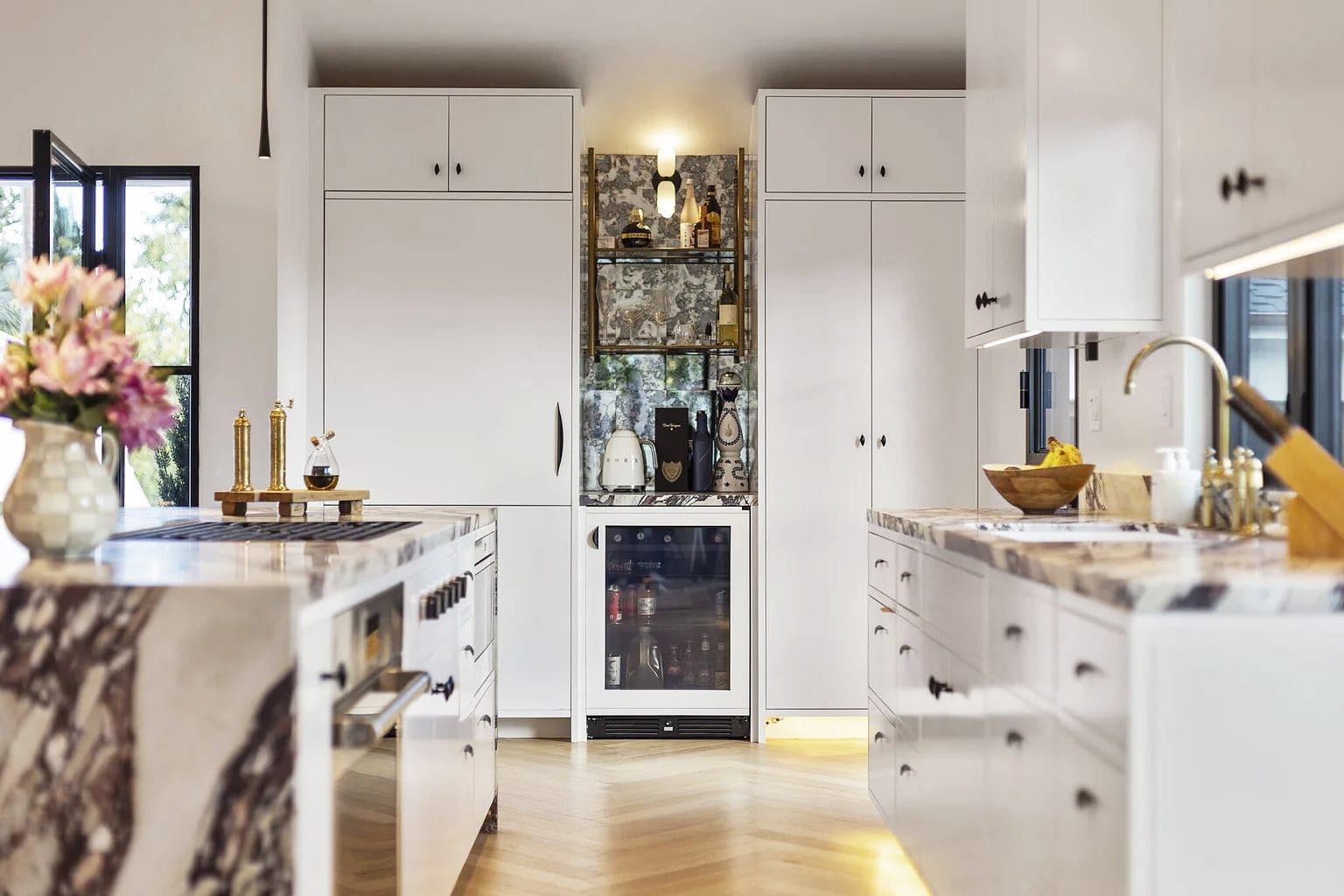 Kitchen bar nook with an antiqued mirrored tile backsplash, brass shelving, and a wine fridge, DHRH San Roque renovation