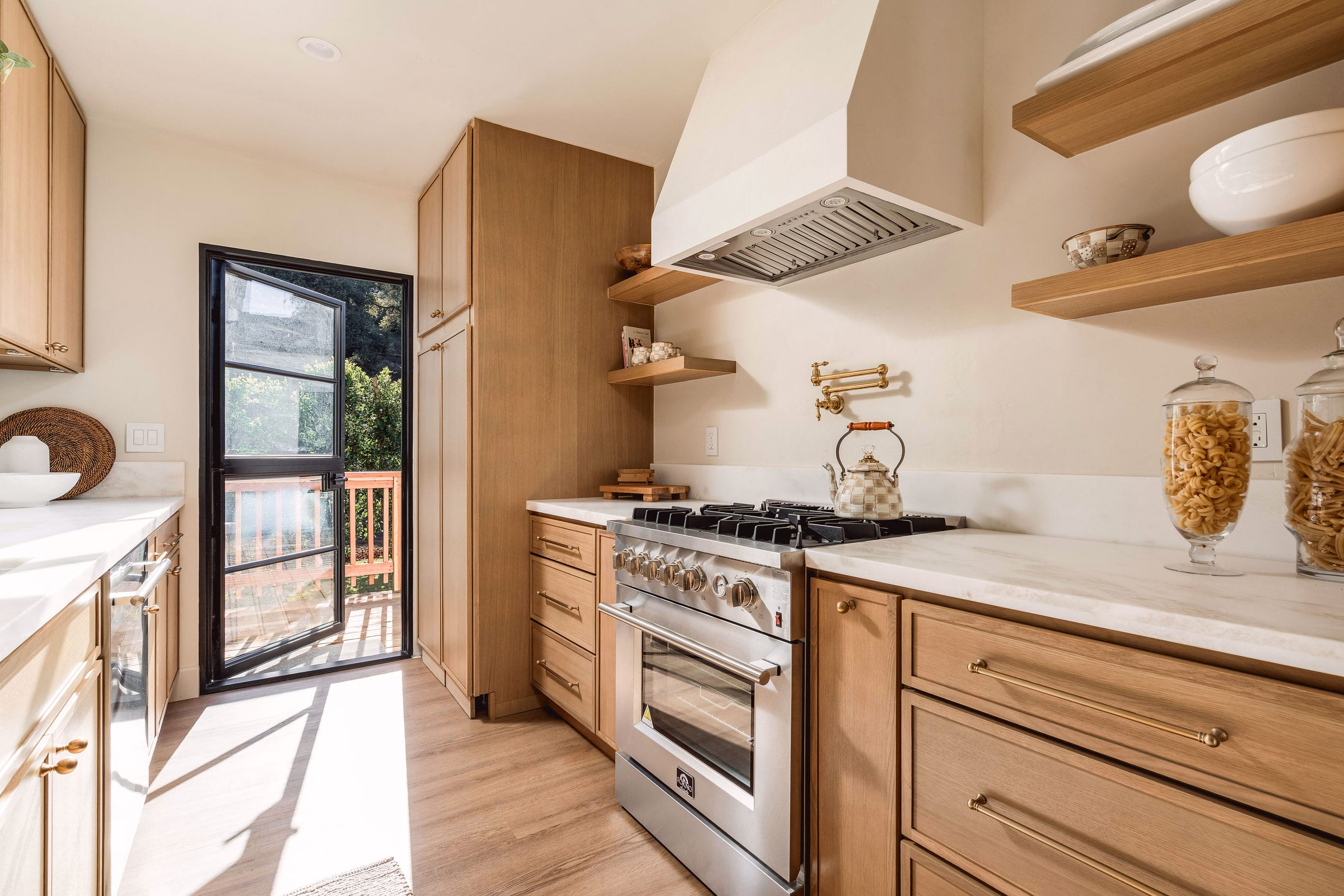 White oak galley kitchen with a plaster hood, marble counters, and a steel-framed door to the deck, DHRH West Side renovation