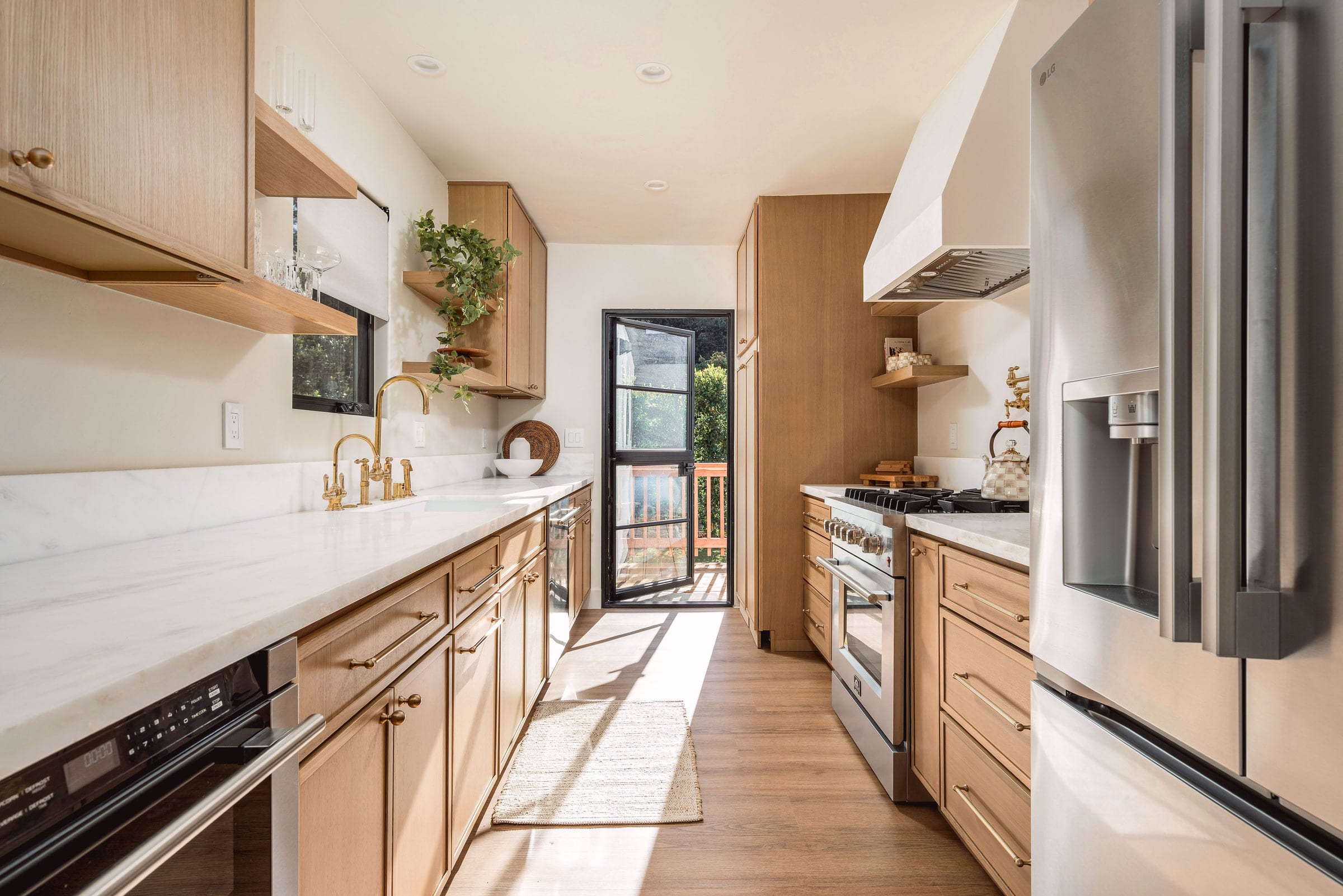 Long galley kitchen with white oak cabinetry, marble counters, a gas range, and a stainless steel refrigerator, DHRH West Side renovation
