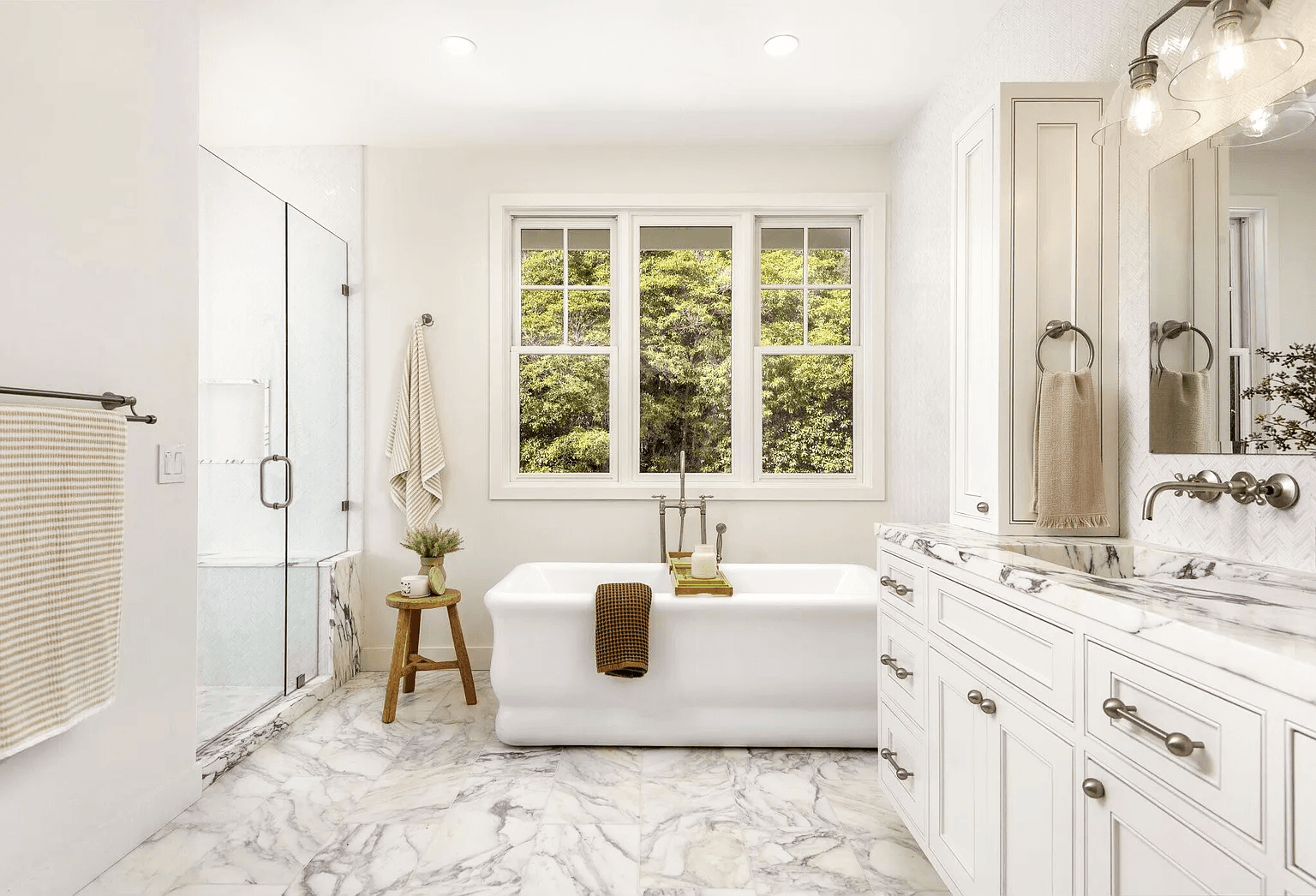 Open kitchen with a veined marble island, woven leather bar stools, and white oak floors, DHRH Montecito renovation